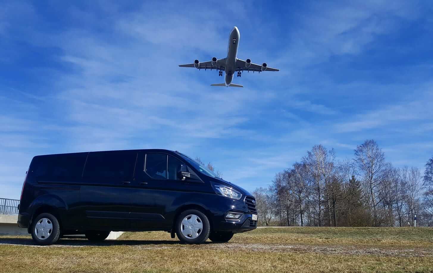 Schwarzer Van von 0800shuttle, mit über diesen gleitenden Flugzeug.